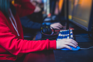 Female gamer, cyber sport e-sports tournament, professional girl gamers, close-up on gamer's hands on a keyboard, pushing button,  in a cyber games arena club, girls playing and streaming fps game