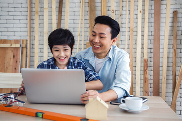 Obraz premium Asian father and son using laptop computer together.