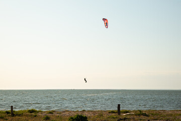 A man is silhouetted on a kite surfboard.