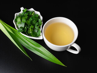 Pandanus aromatic herbs hot in a cup with leaves on a dark background.
