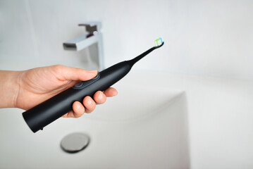 Woman holding black electric toothbrush. Smart electric toothbrush. Modern technology for health. Healthy teeth. Dentistry.