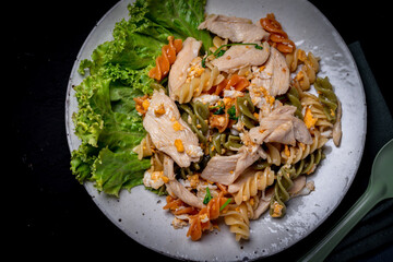 Macaroni stir fried with chicken in ceramic plate on black background
