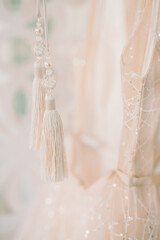 Composition - tassels on a hanging wedding dress. Peach colour.