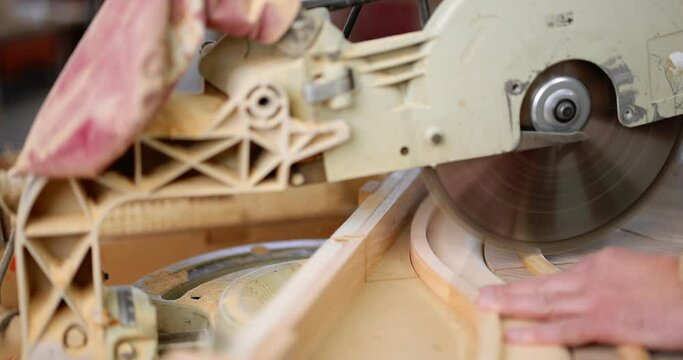 Carpenter sawing wood product with electric circular hand saw at the factory, close-up