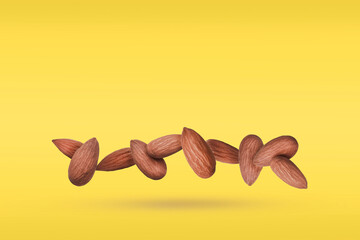 Whole Almonds nuts  in a row Falling  on a  Yellow Background. Food Levitation Concept.Copy Space...