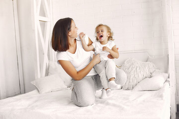 Obraz na płótnie Canvas Beautiful woman with child. Woman in a white t-shirt. Little daughter in a bedroom