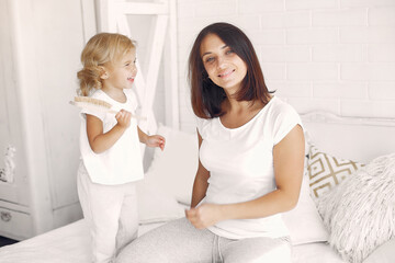 Beautiful woman with child. Woman in a white t-shirt. Little daughter in a bedroom
