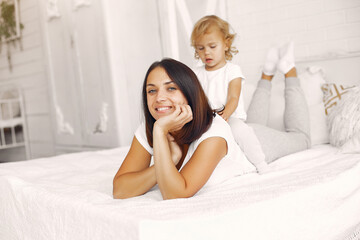Obraz na płótnie Canvas Beautiful woman with child. Woman in a white t-shirt. Little daughter in a bedroom