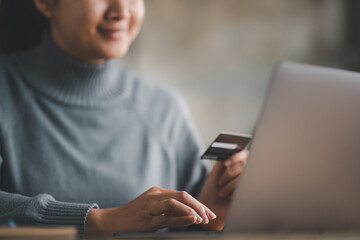 online shopping concepts, woman hands using laptop computer for online shopping at home, Hand holding credit card and Payment Detail page on computer.