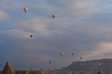 Tourist hot air balloons floating in the cloudy sky in Cappadocia. Cloudy weather. Colorful balloons.