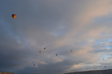 Tourist hot air balloons floating in the cloudy sky in Cappadocia. Cloudy weather. Colorful balloons.