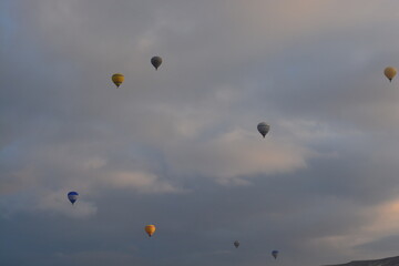 Tourist hot air balloons floating in the cloudy sky in Cappadocia. Cloudy weather. Colorful balloons.