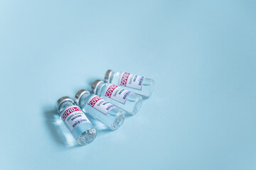 Covid-19 vaccine. Ampoules with coronavirus Sars-Cov-2 jab Injections. Vaccine shortages setback for Its immunization race. Close up vial dose on blue background and place for text. 