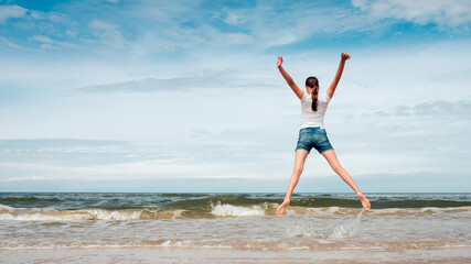 Fototapeta na wymiar Happy girl jumping on the beach at day time