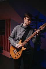 Obraz premium Energetic young man playing rock music on guitar