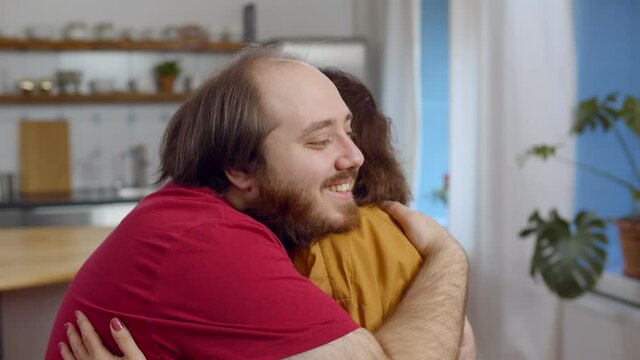 Loving elderly mother cuddling adult son and smiling at home together