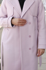 pink woolen coat closeup detail with model hands on city street background