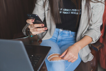 Young woman checking and typing on her cell phone.