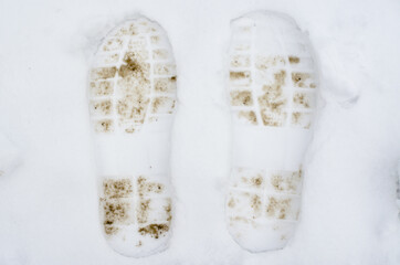 Dirty footprints of a man on white snow.