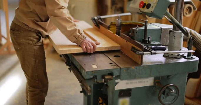 Capenter grinding wooden planks on the old machine at the joinery shop