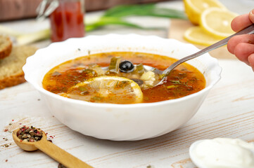 Traditional russian soup solyanka. Hodgepodge soup with meat, lemon and olives. Served with sour cream