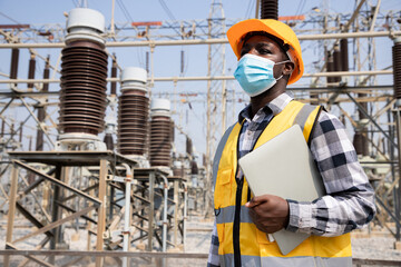 Portrait of handsome engineering man holding laptop and wear hardhat in front of High power power...