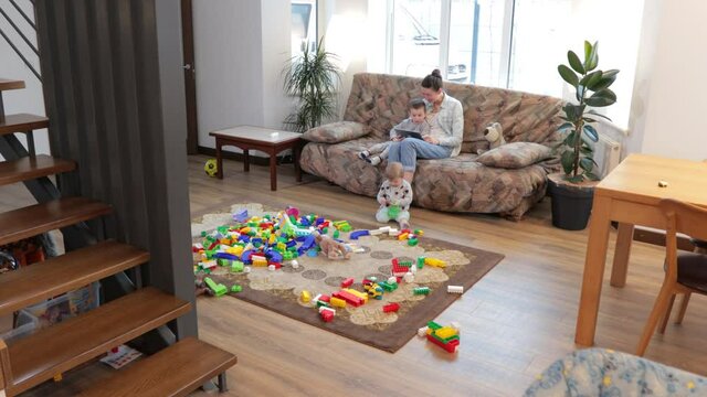 Mother and children playing with toy brick construction at home