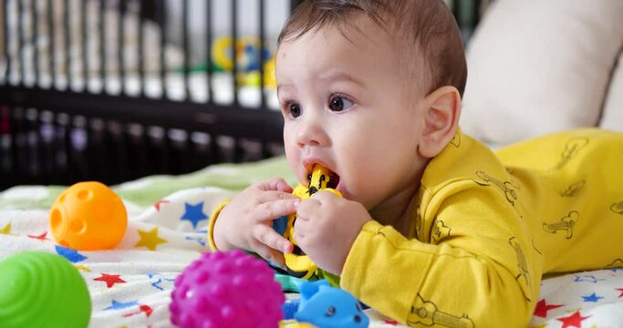 infant, childhood concept - close-up of smiling happy Baby plays with a teether. Teeth cutting. First teeth. Joy toothless 7 months baby bite, gnaws teether toy
