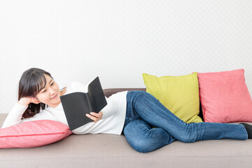 Woman lying on the sofa reading a book