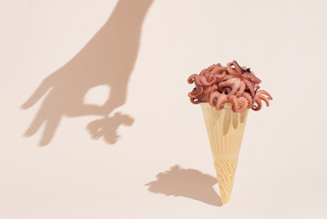 Creative arrangement with fresh octopuses in ice cream waffle cone over soft pastel beige background. Creative idea seafood summer background.