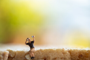 Miniature people : Woman taking picture sitting on bread, green nature background