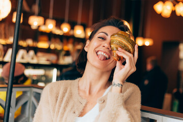 Portrait of cheerful contented woman in cafe with pistachio croissant