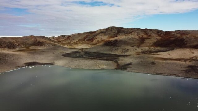 Moraine Landscape and meltwater lake in Kangerlussuaq, Greenland. Aerial panning to left.