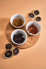 Three white flats with nuts and raisins stand on a bamboo stand. Flat lay
