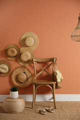 Wooden chair with bag and straw hats on brown wall. Interior design