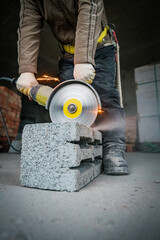 a builder saws a building block with a grinder