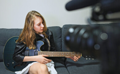 Teenage girl with semi-acoustic guitar in front of the video camera.