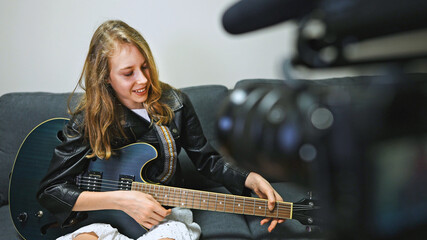 Teenage girl with semi-acoustic guitar in front of the video camera.