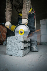 a builder saws a building block with a grinder
