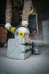 a builder saws a building block with a grinder
