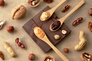 Concept for natural and vegetarian products. Butter, nut paste in wooden spoons with ingredients on a light background. Homemade Raw Organic Hazelnut, Peanut, Walnut. Top view, flatlay, pattern