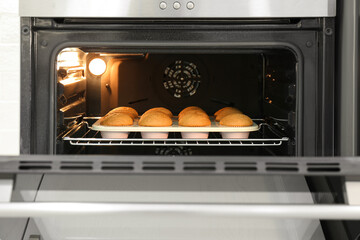 Baking pan with cupcakes in modern oven