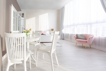 Luxurious and expensive interior of an open-plan apartment in light colors. Stylish modern bedroom with minimal design, dining area and guest space.