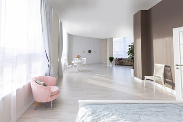 Fototapeta na wymiar Luxurious and expensive interior of an open-plan apartment in light colors. Stylish modern bedroom with minimal design, dining area and guest space.