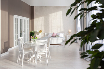 Luxurious and expensive interior of an open-plan apartment in light colors. Stylish modern bedroom with minimal design, dining area and guest space.
