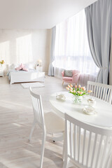 Luxurious and expensive interior of an open-plan apartment in light colors. Stylish modern bedroom with minimal design, dining area and guest space.