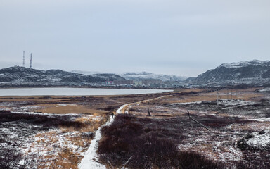 A narrow path that goes into the distance to the Arctic village located between the polar hills.