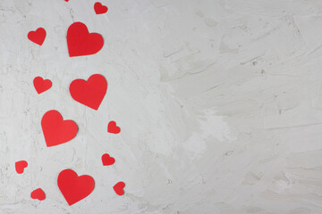 Valentine's day red paper hearts of various sizes on light concrete background flat lat composition mokup ready