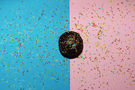 Brown muffin on the blue-pink background with sprinkles.