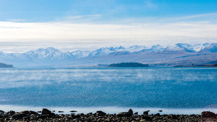 A foggy winter day at the Lake Tekapo on New Zealand‘s South Island, snow capped mountains, the Southern Alps, in the distance 